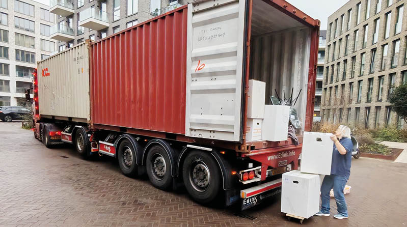 A man is loading a white refrigerator into a red semi truck. AI generated content