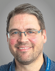 A man wearing a purple sweater. Description generated by AI