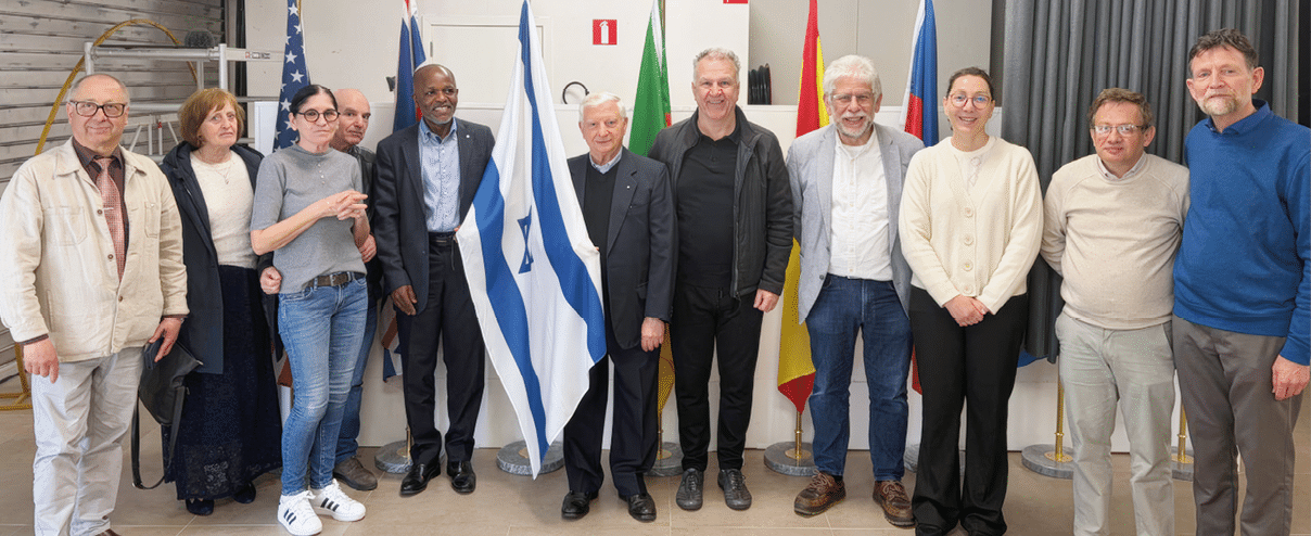 A group of people standing in front of a flag. Description generated by AI