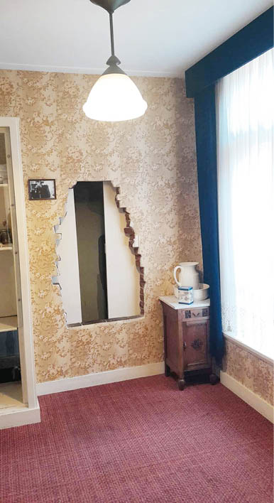 A room with a red carpet and a hole in the wall. Description generated by AI