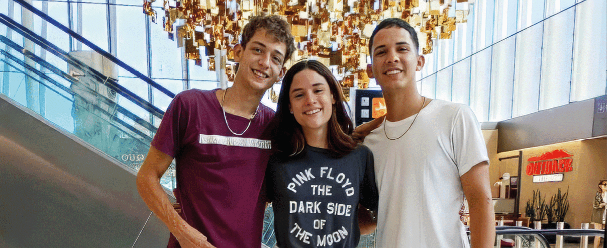 A group of three people standing in front of a large heart shaped sculpture. Description generated by AI