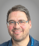 A man wearing a purple sweater. Description generated by AI