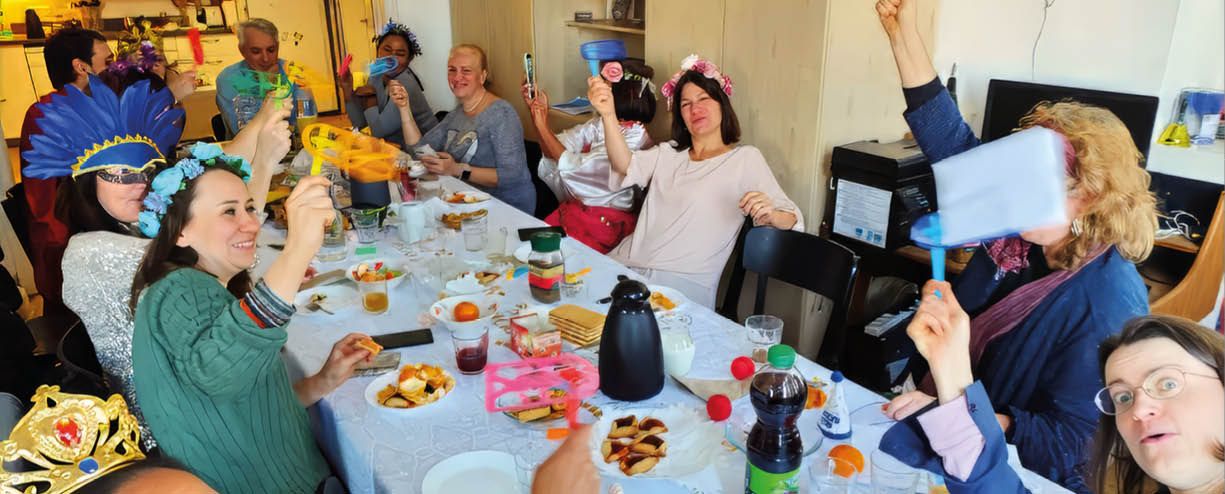 A group of people sitting around a table with plates of food and drinks. Description generated by AI