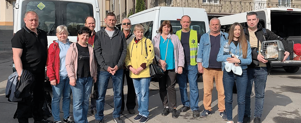 A group of people standing in front of a white van. Description generated by AI