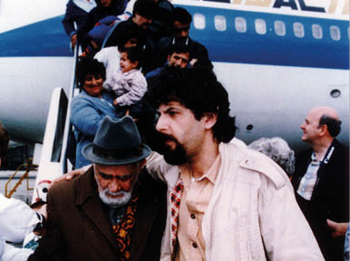 A man in a brown jacket and a man in a black jacket are standing next to each other. Description generated by AI
