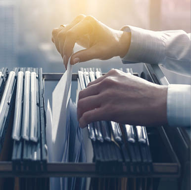 Professional female office clerk searching files and paperwork in the filing cabinet