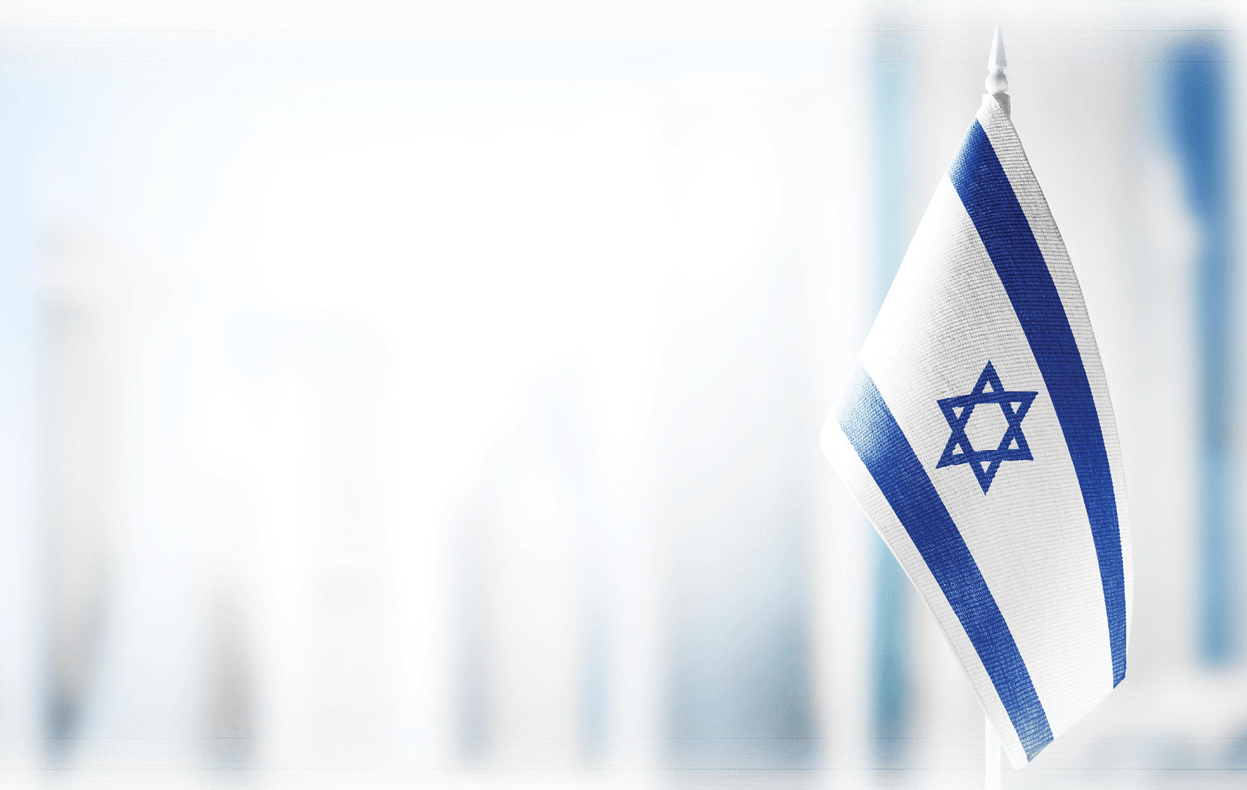A small flag of Israel on the background of an urban abstract blurred background.