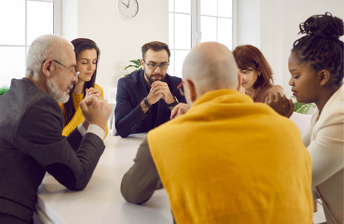 Diverse people praying together  Group of different religious multiracial multiethnic males and females sitting around table and saying prayer of gratitude, thanking God for His amazing grace