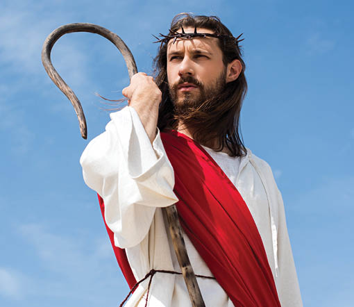 Jesus in robe, red sash and crown of thorns standing with wooden staff against blue sky and looking away