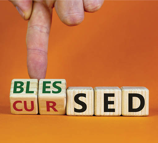 Cursed or blessed  Male hand flips a wooden cube and changes a word 'cursed' to 'blessed' or vice versa  Beautiful orange background, copy space  Religious and cursed or blessed concept 