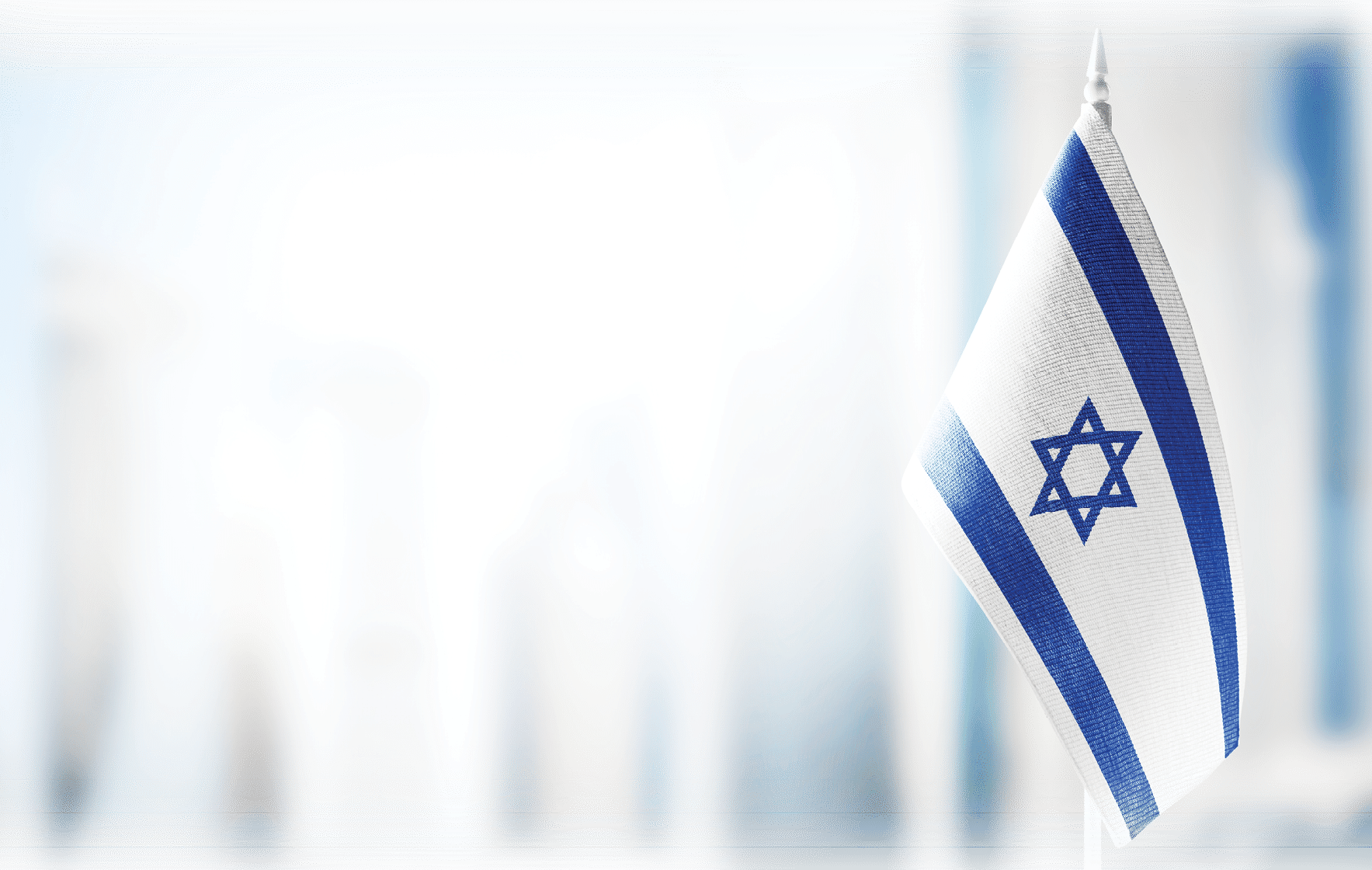 A small flag of Israel on the background of an urban abstract blurred background 