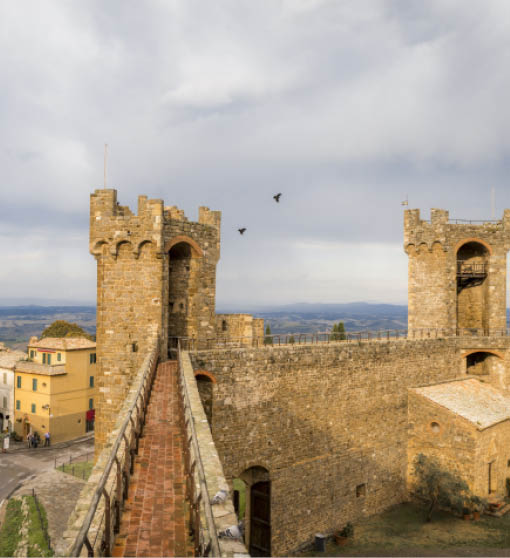 View of tower and wall of the fortress Montalcino Fortezza, city streets and bell towers in Montalcino, Tuscany, Italy