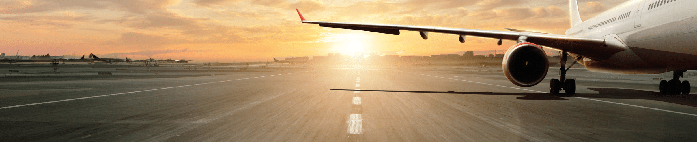 Parked airplane on runway with dramatic sunset light. Travel and transportation concept.
