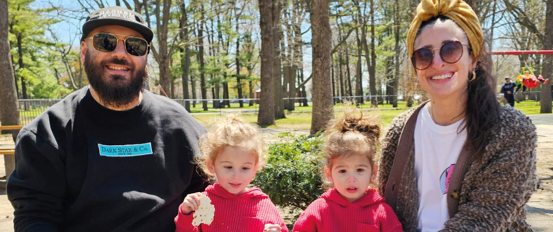 A man and two children sitting on a bench. Description generated by AI