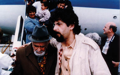 A man in a brown jacket and a man in a black jacket are standing next to each other. Description generated by AI
